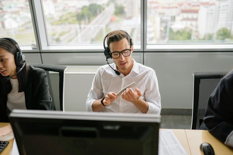 Call center agents wearing headsets and working at their desks in a modern office setting.