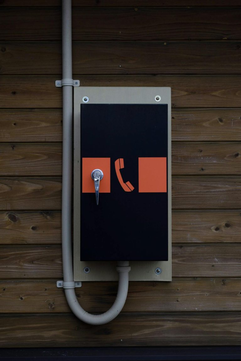 Emergency telephone box on a wooden wall outdoors, featuring a modern design.